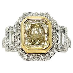 a fancy yellow diamond ring set with two baguetts and diamonds on the sides