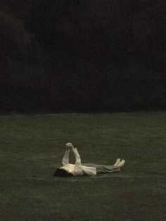 a person laying in the grass with their legs spread out and one hand up above his head