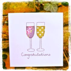 congratulations card with two champagne glasses and flowers on the bottom, in front of leaves