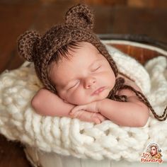 a newborn baby is sleeping in a bucket wearing a brown bear hat and crocheted diaper