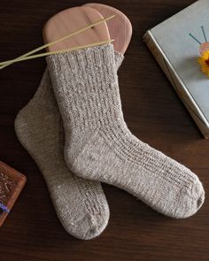 a pair of socks sitting on top of a wooden table next to a book and flower