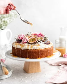 someone is spreading icing on a cake with figs and flowers in the background