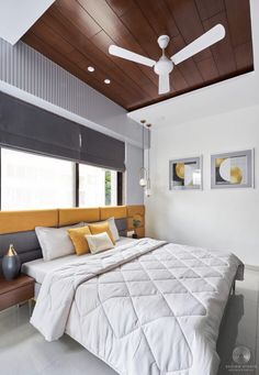 a white bed sitting under a ceiling fan in a bedroom next to a wooden headboard