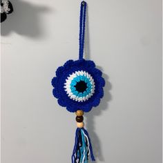 a blue and white crocheted eyeball hanging from a hook on a wall