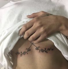 a woman's stomach with flowers on it and a hand touching the side of her belly