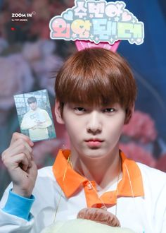 the young man is holding up a card with an image of himself in front of him