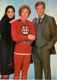 two men and a woman are posing for a photo in matching outfits, one is wearing a red suit