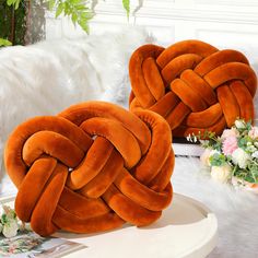 two orange pillows sitting on top of a white table