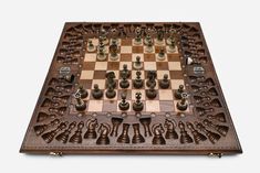 a wooden chess board with metal pieces on it and an intricately carved chess set in the middle