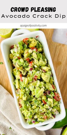 a white bowl filled with guacamole salad next to sliced limes and cilantro