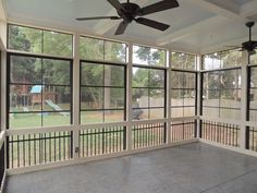 an empty room with large windows and a ceiling fan