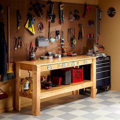 a workbench with tools hanging on the wall next to it and two drawers