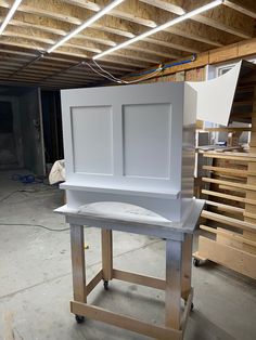 a large white cabinet sitting on top of a wooden stand in a garage next to shelves