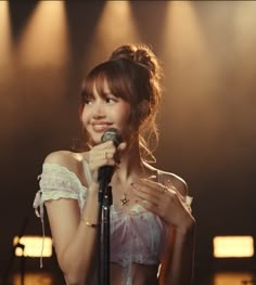 a young woman holding a microphone in front of a stage with spotlights on it