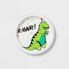 a white plate with a green dinosaur holding a party hat that says rawr on it