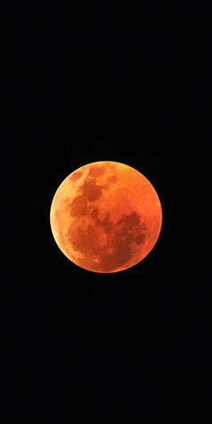 an orange moon is seen in the dark sky