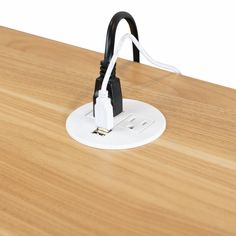 a close up of an electrical outlet on a wooden table with a white cord attached to it