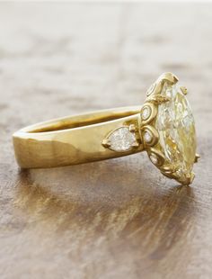 a yellow diamond ring sitting on top of a wooden table