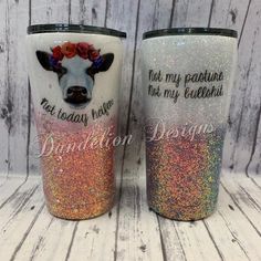 two personalized tumbles with glitter on them, one has a cow's face and the other has flowers