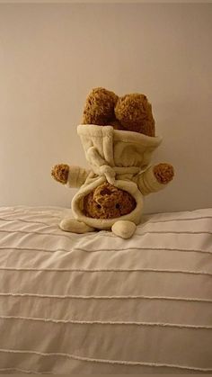 a teddy bear sitting on top of a bed with a towel over it's head