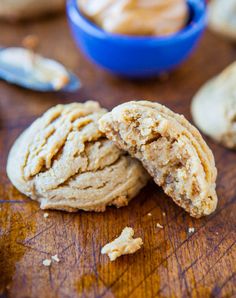 two peanut butter cookies sitting on top of a wooden table next to a blue bowl