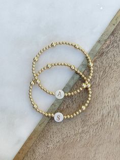 This listing is for ONE beautiful gold filled beaded bracelet with 3mm and 5mm gold filled beads, and a gorgeous shell bead w/gold letter of your choice.  SO beautiful to wear on its own or perfect to layer with your bracelet stack.  Versatile and classic- a treat for yourself or makes the best gift for your loved ones! Please note- the distribution of the 3mm and 5mm beads may be different than pictured, depending on size, but it will look very similar to the samples.   If unsure of sizing, mea Gold Beaded Bracelet With Tiny 14k Gold Filled Beads, Gold 14k Gold-filled Tiny Beaded Bracelets, Dainty Beaded Name Bracelet, Dainty Beaded Name Bracelet With Round Beads, Personalized Gift Gold Beaded Round Bracelets, Personalized Gold Beaded Bracelets, Personalized Gold Round Beaded Bracelets, Personalized Gold Beaded Bracelet, Gold Hypoallergenic Name Bracelet With Round Beads