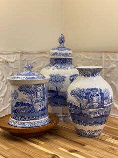 three blue and white vases sitting on top of a wooden table next to each other