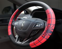 the steering wheel cover is red and black with a spiderman design on it's side