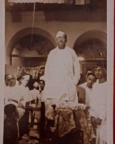 an old black and white photo of a man standing in front of a group of people