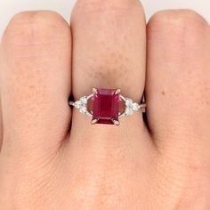 This beautiful ring features an emerald-cut ruby with a triad of natural earth-mined diamonds on both sides, all set in solid 14K white gold. This ring can be a lovely July birthstone gift for your loved ones! This ring is made with solid 14K Gold and naturally Earth-mined SI / G-H diamonds. If you're interested in purchasing this setting with a different center stone please message us! Fine Jewelry Ruby Ring With Radiant Cut Center Stone, Radiant Cut Ruby Ring In Fine Jewelry Style, Radiant Cut Ruby Ring Fine Jewelry, Red Emerald Cut Diamond Rings, Radiant Cut Ruby Ring With Center Stone, Emerald Cut Ruby Ring With Diamonds For Anniversary, Emerald Cut Ruby Ring With Diamond Accent Stones, Fine Jewelry Ruby Ring With Radiant Cut Diamond, Emerald Cut Ruby Ring For Anniversary