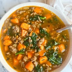 a white bowl filled with meat and vegetable soup on top of a marble countertop