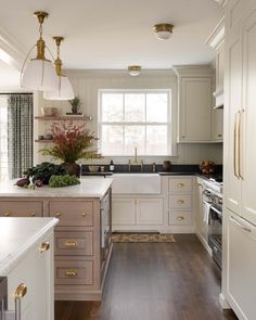 a kitchen with white cabinets and wood floors, an oven, sink, dishwasher and window