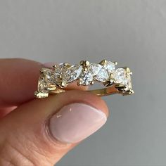 a woman's hand holding a yellow gold ring with five diamonds