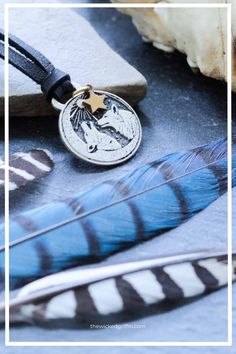 a blue feather is laying next to a silver and black pendant with a gold star on it