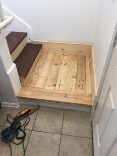 a wooden step in the corner of a room next to a door and some tools