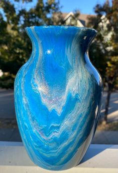 a large blue vase sitting on top of a white table next to some trees and buildings