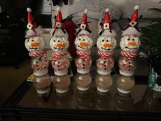 snowmen in hats and scarfs are lined up on a coffee table with candy