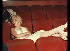 a woman in white dress laying on red seats