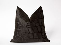 a black pillow with an animal print pattern on the front and back, sitting on a white surface