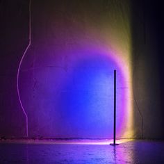 a purple and blue light shines brightly on the wall next to a black pole