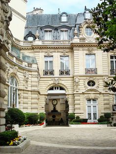 a large building with a clock on it's front door and landscaping around the entrance