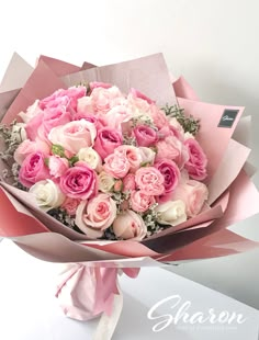 a bouquet of pink and white roses wrapped in paper