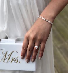 a close up of a person's hand holding a white box with a diamond ring on it