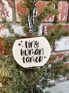 a ceramic ornament hanging from a tree with the words tiny human tamer on it