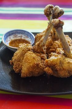 fried chicken with dipping sauce on a black plate