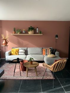 a living room filled with lots of furniture next to a wall covered in potted plants