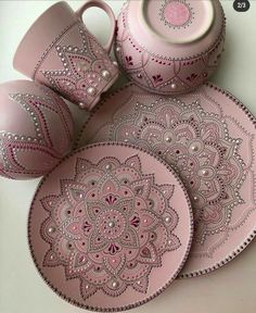 three pink plates and two cups with beaded designs on them