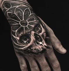 a hand with a skull and flower tattoo on it