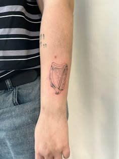 a person with a tattoo on their arm holding a small harp in his left hand