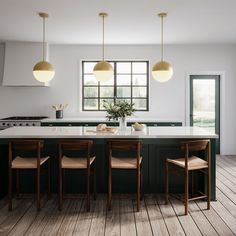 a kitchen with green cabinets and white counter tops, two pendant lights over the island